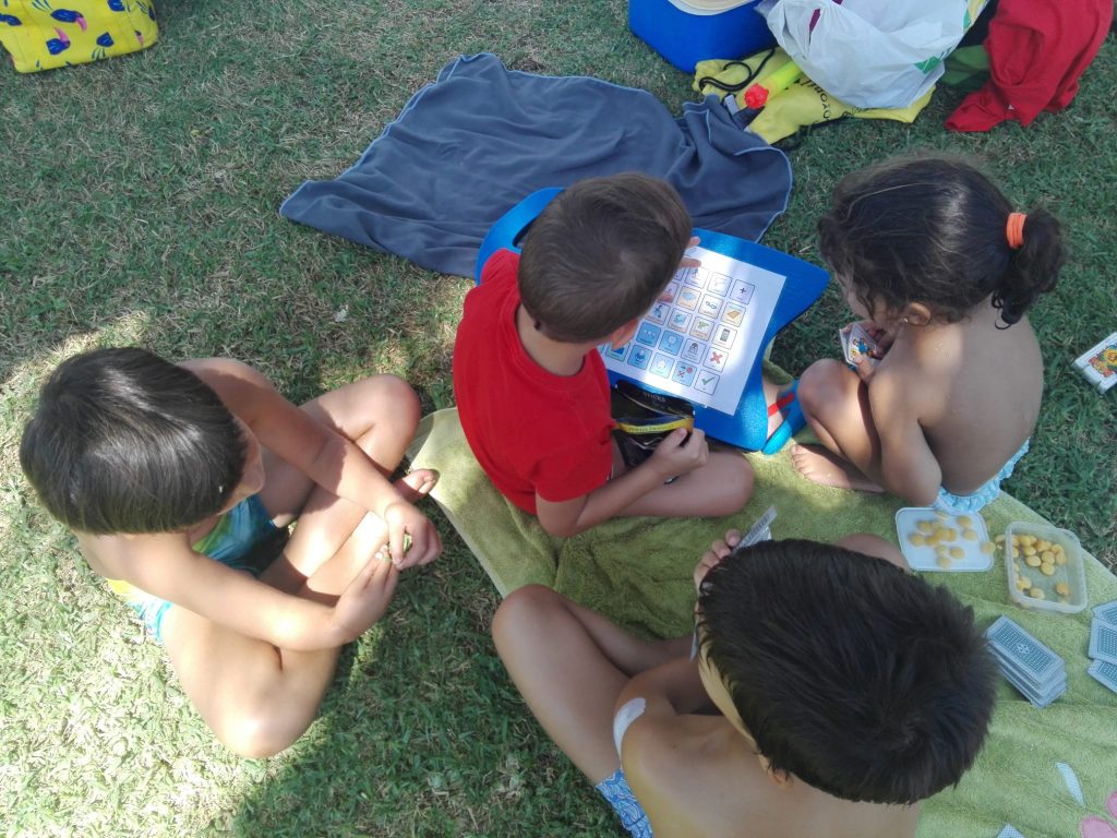 Un grupo de niños usando un comunicador sencillo en la piscina. Adherido a una tabla de aprender a nadar.