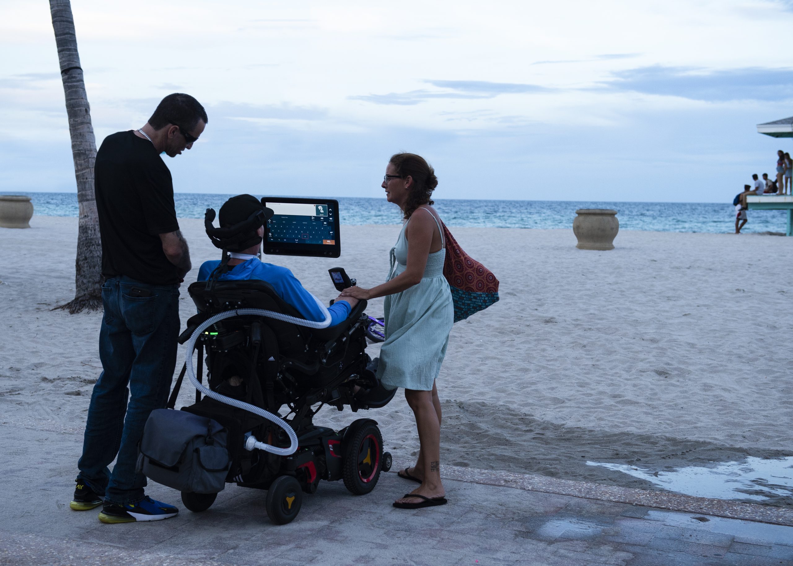 Familia en el paseo marítimo. Usuario afectado de ELA con su comunicador dinámico.